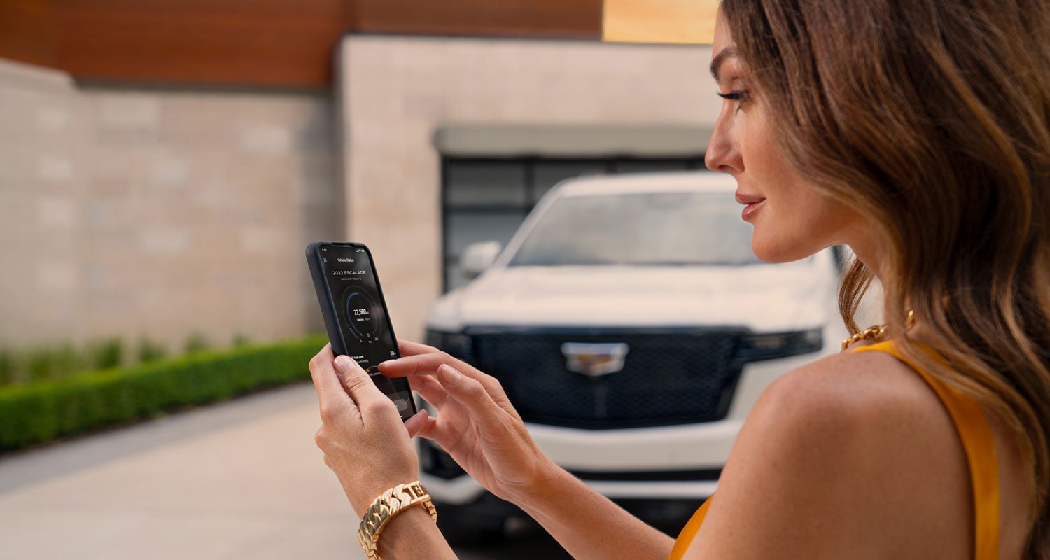 lady checking her mobile with a Cadillac vehicle background | Performance Cadillac in Carroll OH